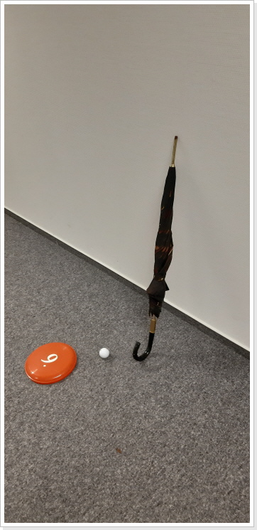 Bürogolf mit dem Regenschirm spielen.